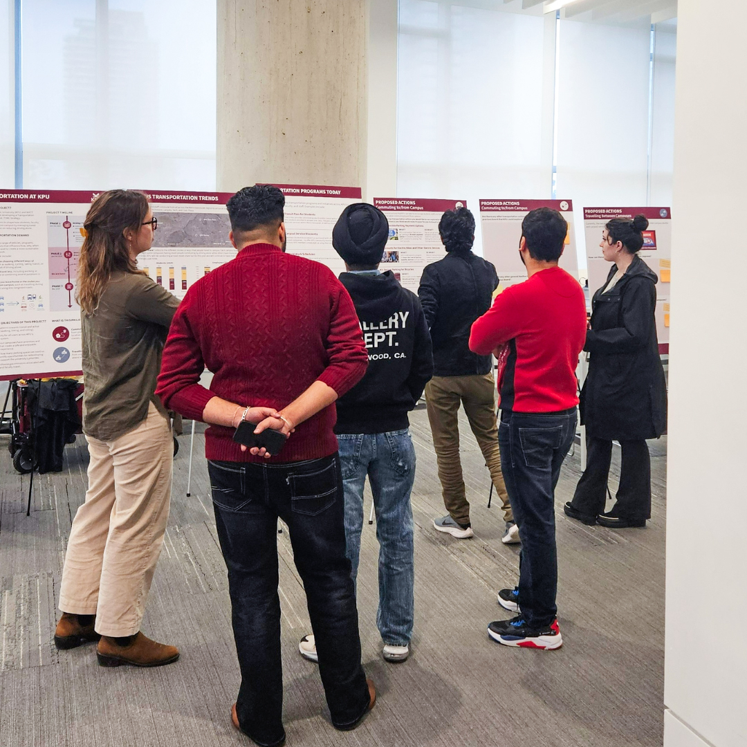 six people facing away from the camera looking at boards displayed on easels 